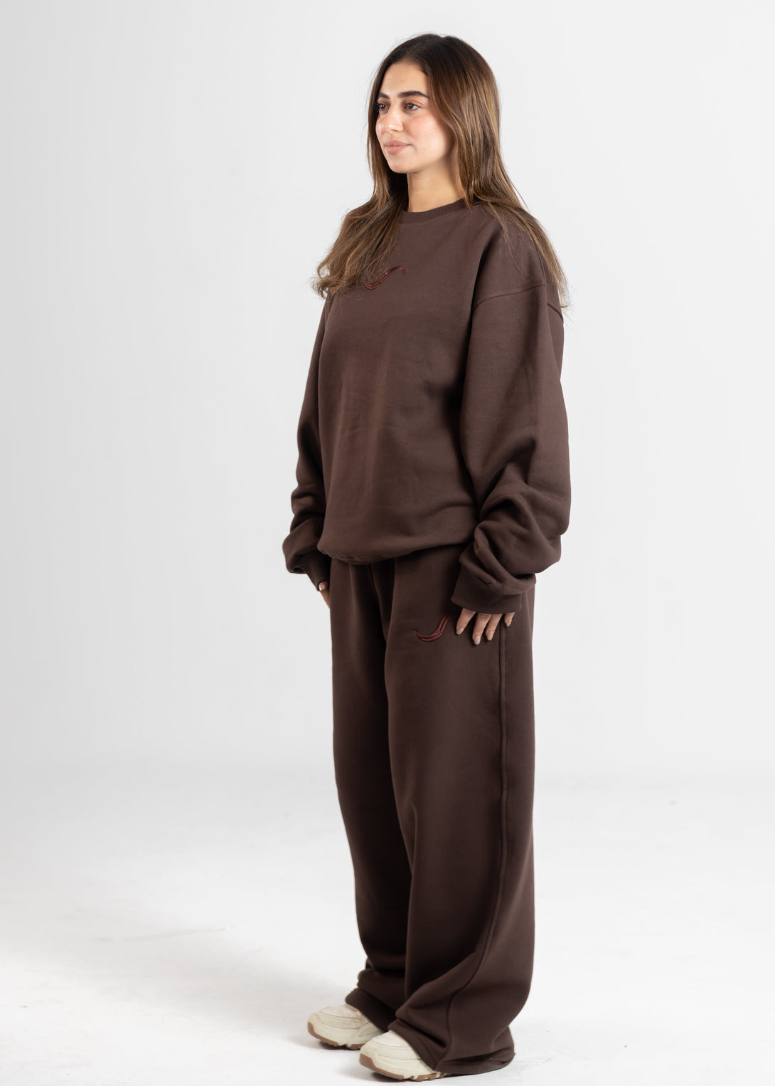 Woman wearing a brown sweatshirt and pants on a white background