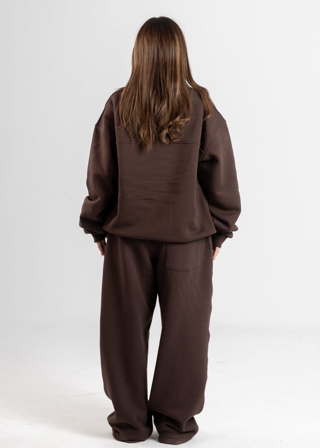 Person wearing a brown tracksuit against a white background