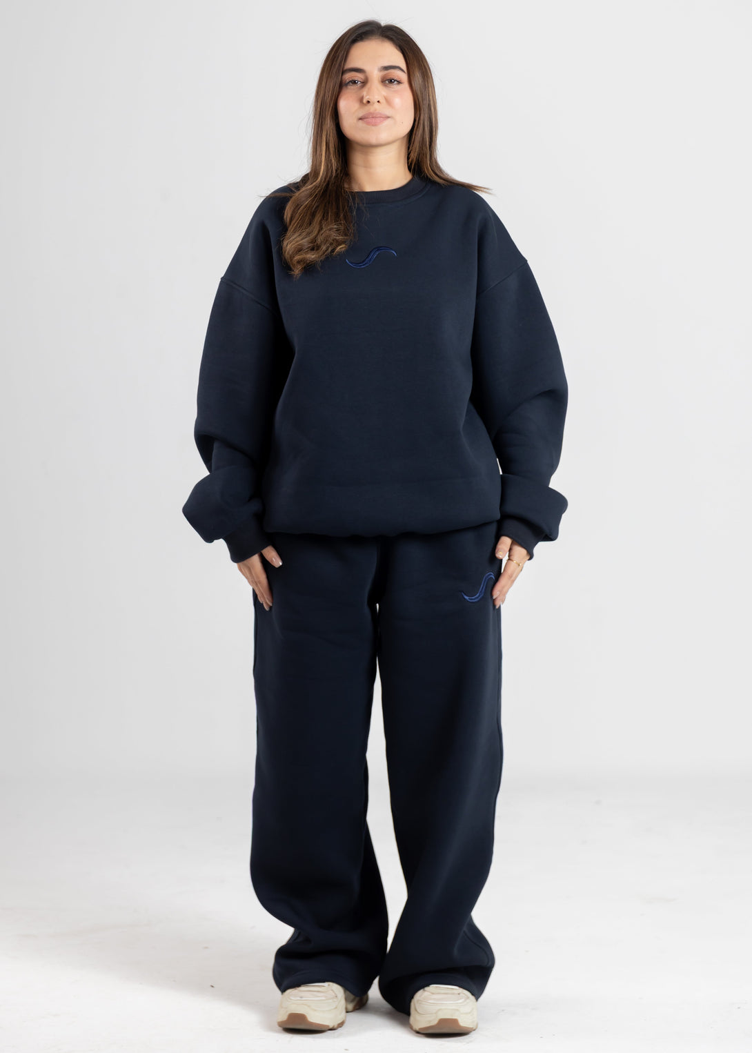 Person wearing a navy blue sweatshirt and pants on a white background