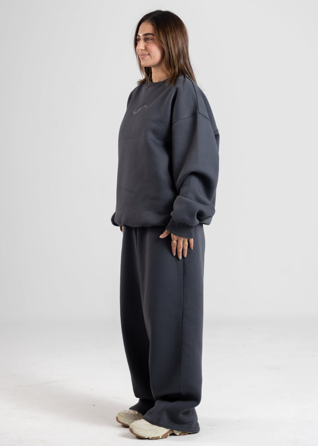 Person wearing a dark gray sweatshirt and pants on a white background