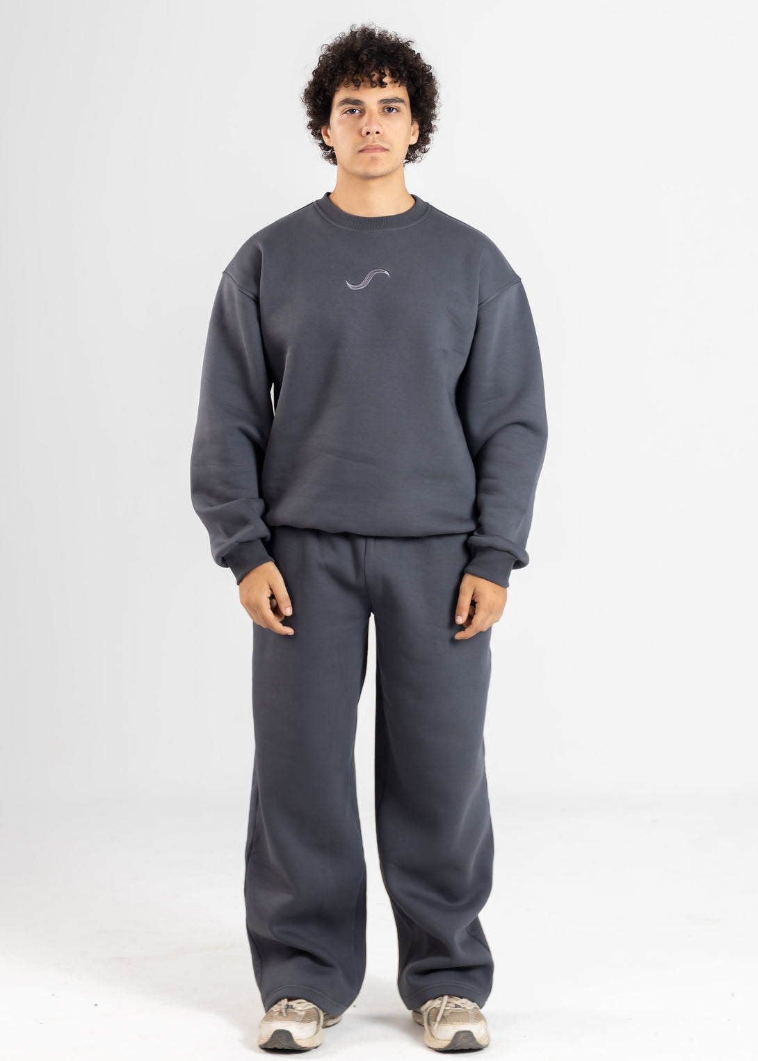 Person wearing a gray sweatshirt and pants set on a white background