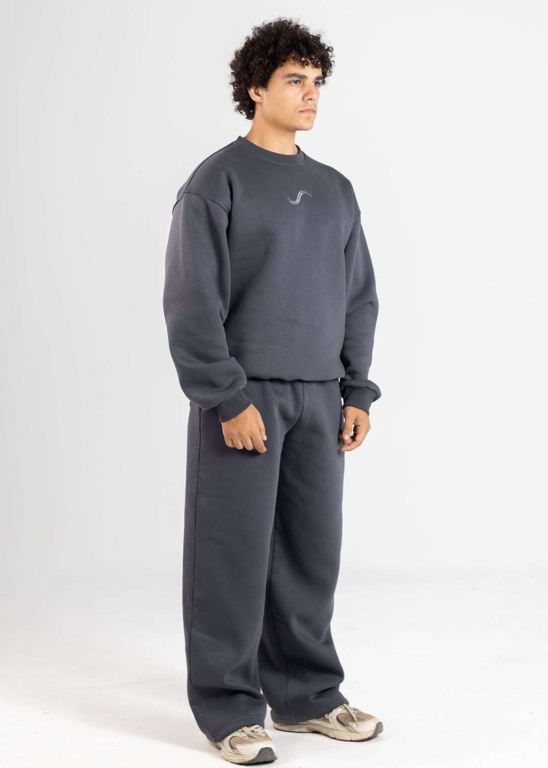 Person wearing a gray sweatshirt and pants set on a white background