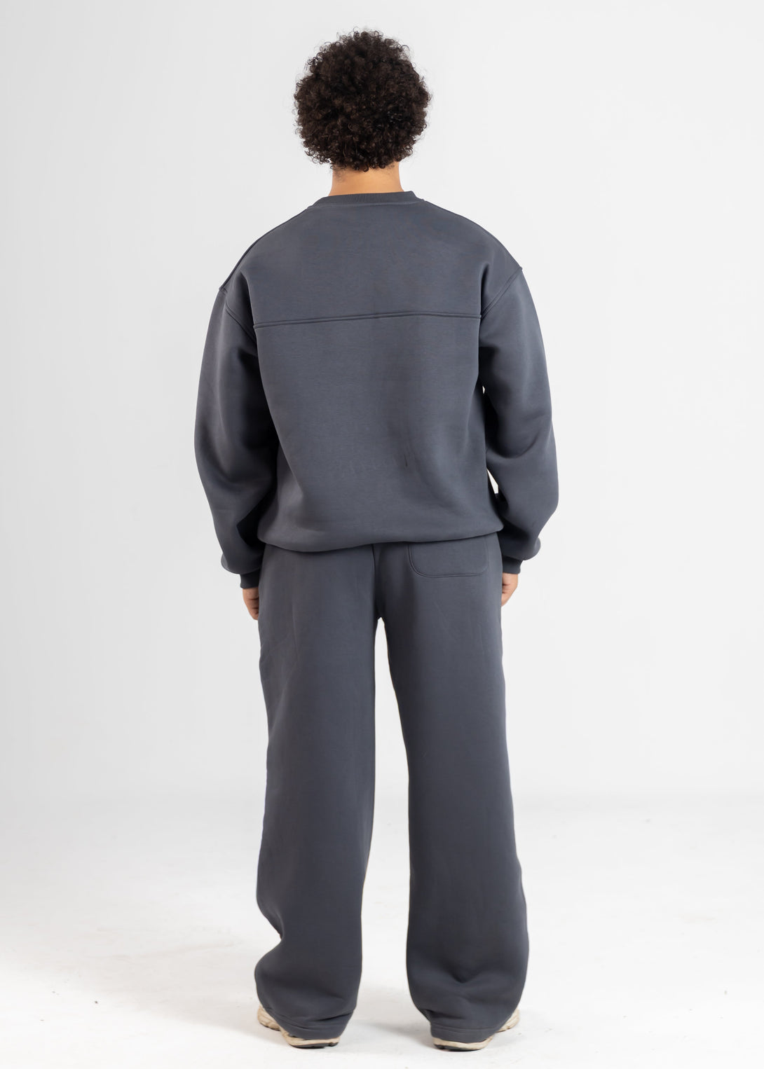 Person wearing a gray tracksuit on a white background